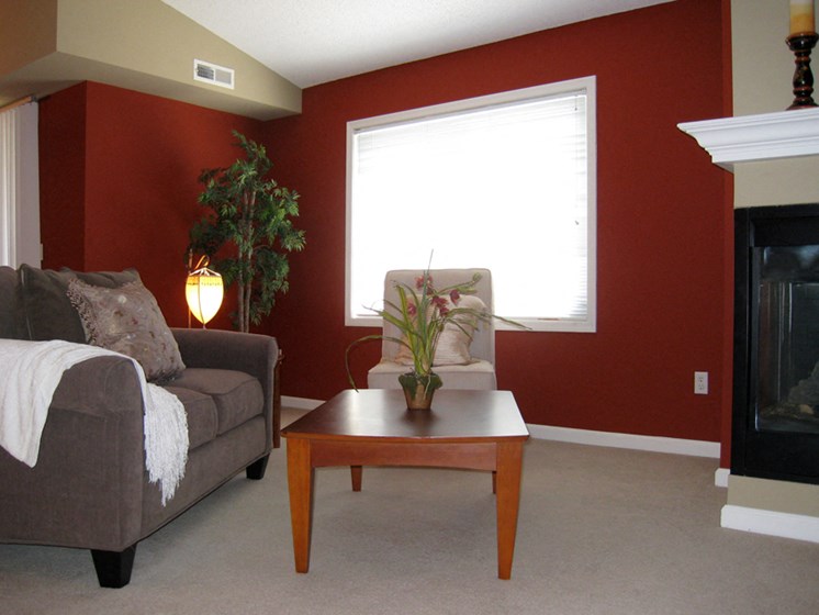 Living room with a gray couch, red walls, and a wooden coffee table